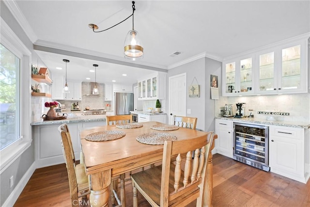 dining space with wine cooler, dark wood-style flooring, crown molding, a dry bar, and recessed lighting