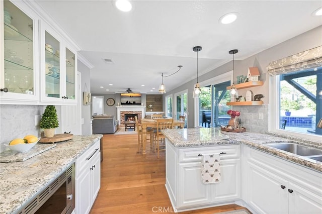kitchen featuring stainless steel microwave, a sink, a lit fireplace, recessed lighting, and backsplash