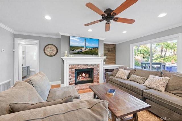living area with recessed lighting, crown molding, a ceiling fan, and a brick fireplace