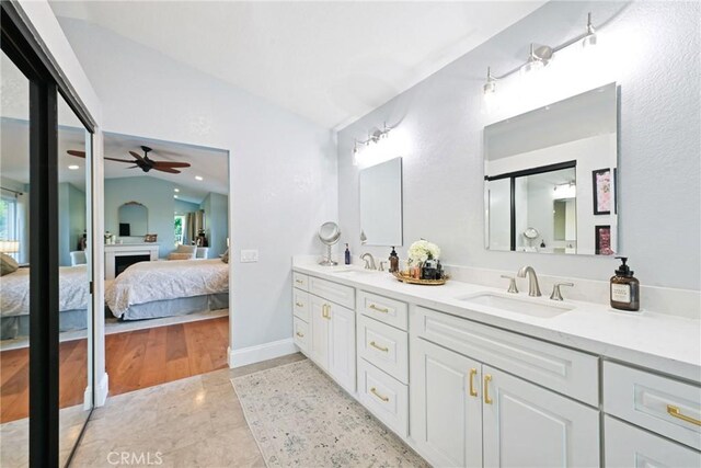full bath featuring ensuite bathroom, vaulted ceiling, a ceiling fan, double vanity, and a fireplace