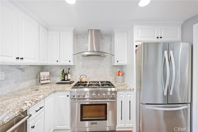 kitchen featuring appliances with stainless steel finishes, wall chimney exhaust hood, white cabinetry, and backsplash