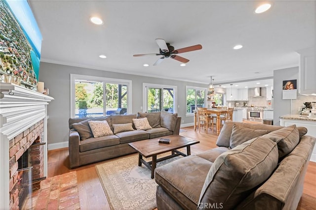 living area with ornamental molding, ceiling fan, recessed lighting, baseboards, and light wood-style floors