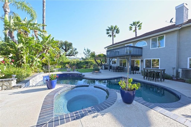 view of swimming pool featuring a patio, outdoor dining area, central AC unit, and a pool with connected hot tub