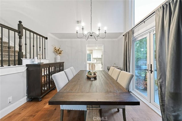 dining space with a chandelier, crown molding, wood finished floors, baseboards, and stairs