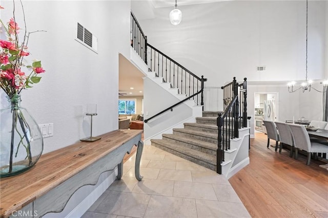stairway with a towering ceiling and a chandelier