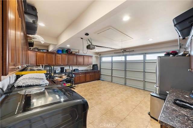 garage featuring a garage door opener, washer / dryer, recessed lighting, and freestanding refrigerator