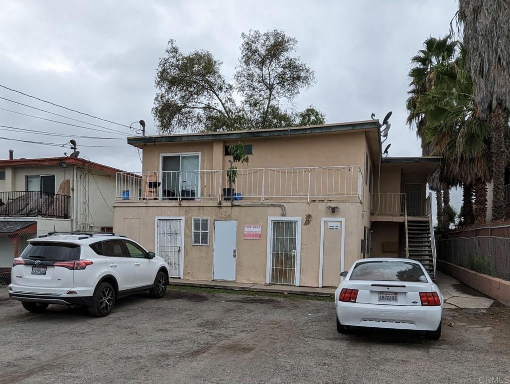view of front of house with stucco siding, stairs, and uncovered parking