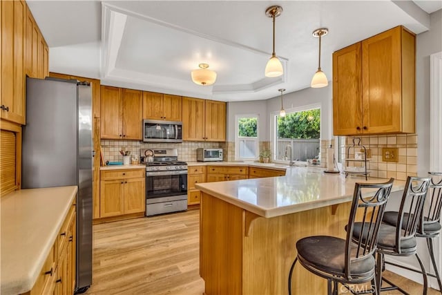 25572 Saltwater Dr, Dana Point, CA 92629 - kitchen featuring stainless steel appliances, a peninsula, light wood finished floors, and tasteful backsplash