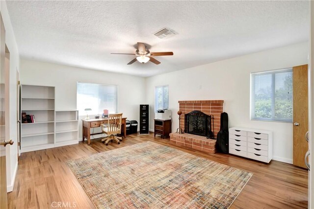 39671 Cherry Valley Blvd, Cherry Valley, CA 92223 - living area featuring wood finished floors, a brick fireplace, a ceiling fan, a desk, and a textured ceiling