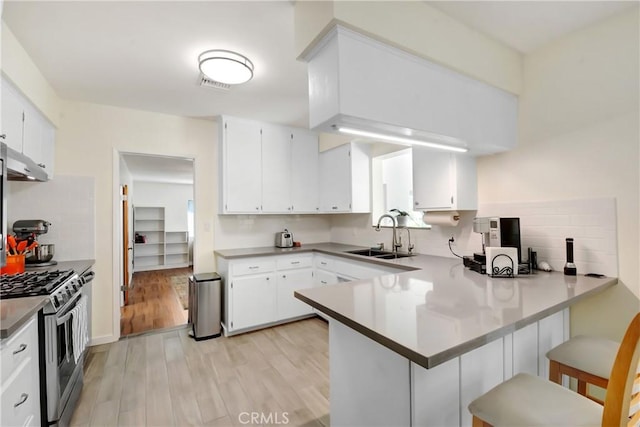 39671 Cherry Valley Blvd, Cherry Valley, CA 92223 - kitchen featuring a sink, gas stove, under cabinet range hood, a peninsula, and backsplash