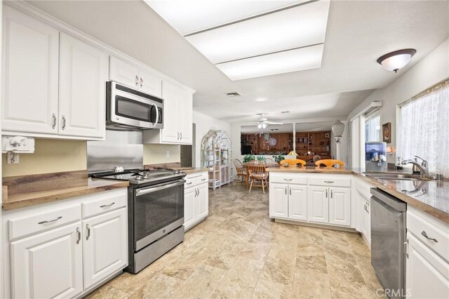 54955 Benecia Trl, Yucca Valley, CA 92284 - kitchen featuring appliances with stainless steel finishes, a sink, white cabinetry, a ceiling fan, and a peninsula
