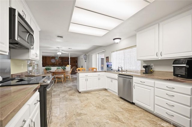54955 Benecia Trl, Yucca Valley, CA 92284 - kitchen with stainless steel appliances, a ceiling fan, a sink, a peninsula, and white cabinets