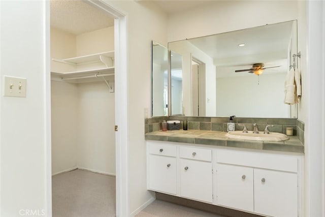 bathroom featuring vanity, ceiling fan, and a spacious closet