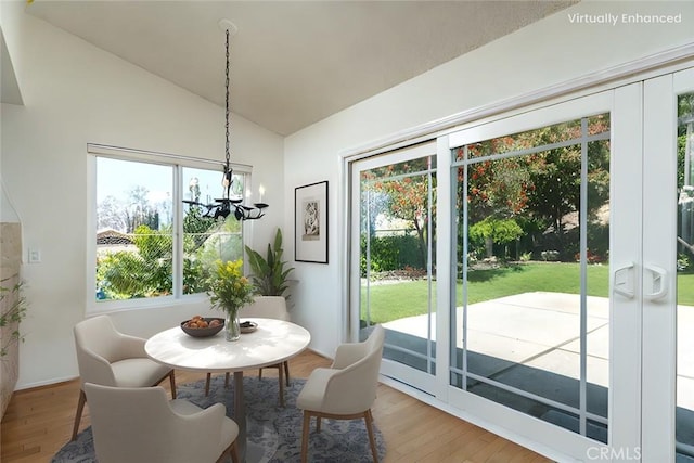 dining space with wood finished floors, a chandelier, and high vaulted ceiling