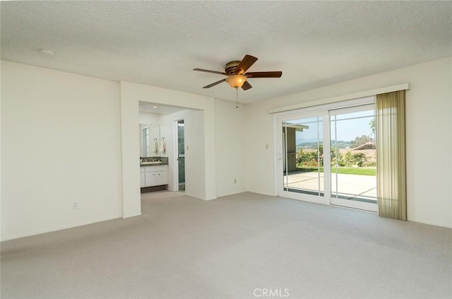 unfurnished room featuring light colored carpet, a ceiling fan, and a textured ceiling