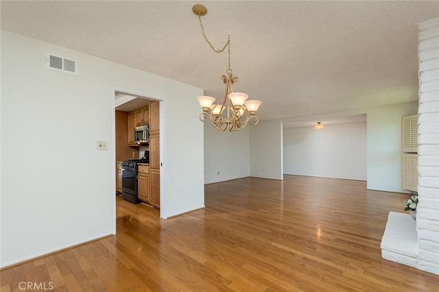 unfurnished dining area with a chandelier and light wood-style flooring