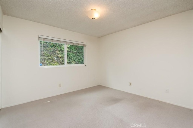spare room featuring carpet, a textured ceiling, and baseboards
