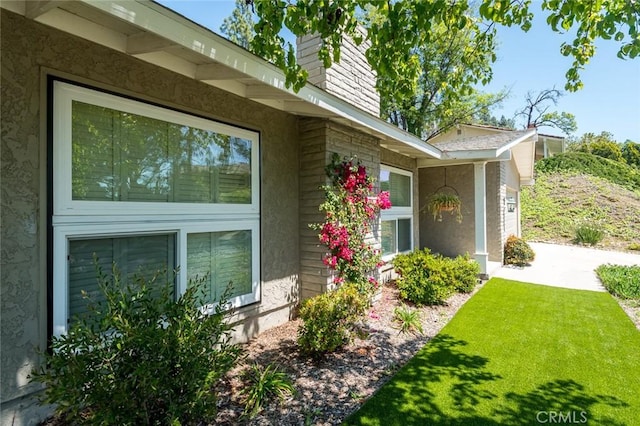 view of side of property with a chimney, stucco siding, a yard, and a garage