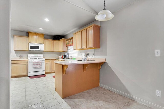 13935 Rincon Rd, Apple Valley, CA 92307 - kitchen featuring white appliances, light brown cabinets, light countertops, a peninsula, and a breakfast bar