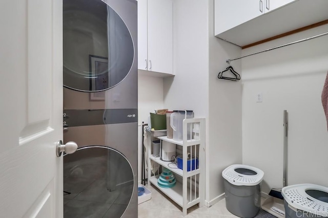 laundry room featuring stacked washer / dryer, cabinet space, and light tile patterned flooring