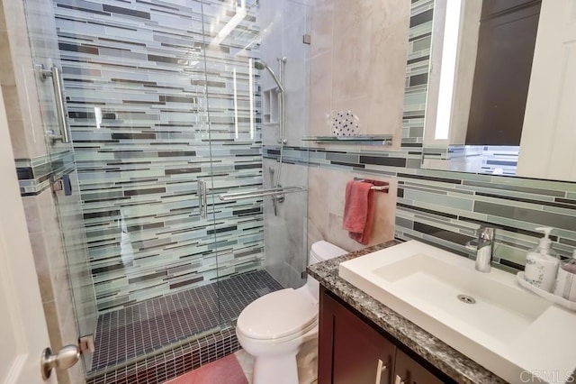 bathroom with toilet, a shower stall, vanity, tile walls, and tasteful backsplash