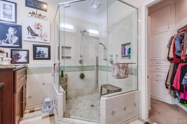bathroom featuring a shower stall, vanity, and tile walls