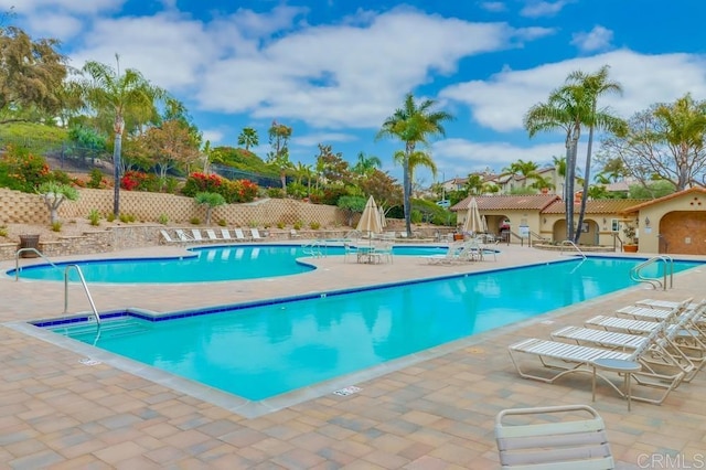 community pool with a patio area and fence