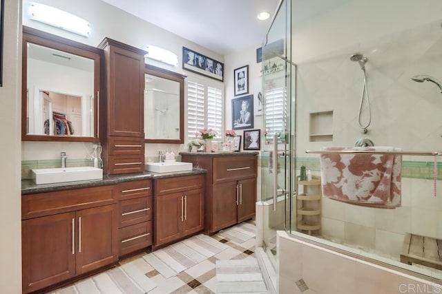 bathroom with a stall shower, double vanity, and a walk in closet