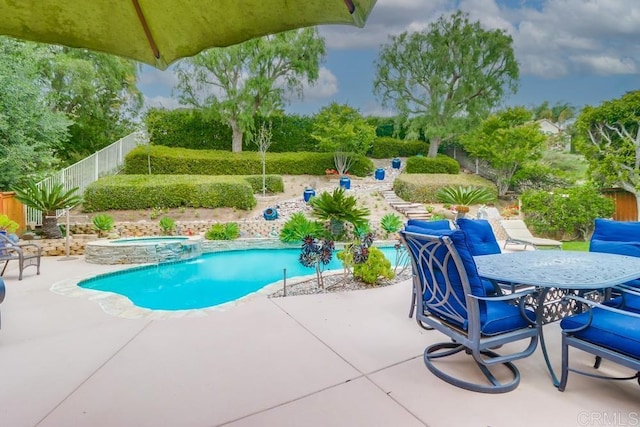 view of swimming pool with a patio area, a fenced backyard, a pool with connected hot tub, and outdoor dining space
