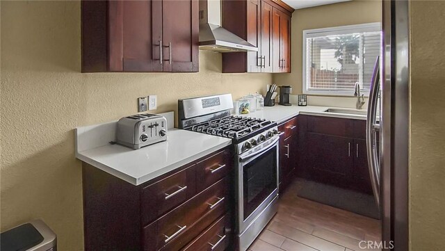 16285 Barbee St, Fontana, CA 92336 - kitchen with stainless steel appliances, wall chimney range hood, a textured wall, light countertops, and dark brown cabinets
