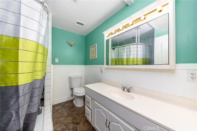 35602 Carter St, Yucaipa, CA 92399 - bathroom with wainscoting, vanity, toilet, a shower with curtain, and stone finish flooring