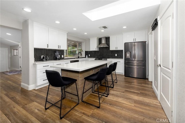 35602 Carter St, Yucaipa, CA 92399 - kitchen with stainless steel fridge, wall chimney exhaust hood, backsplash, light countertops, and a kitchen bar