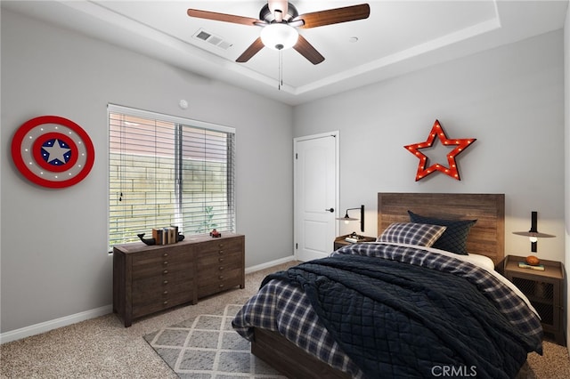 carpeted bedroom featuring baseboards, a raised ceiling, and ceiling fan