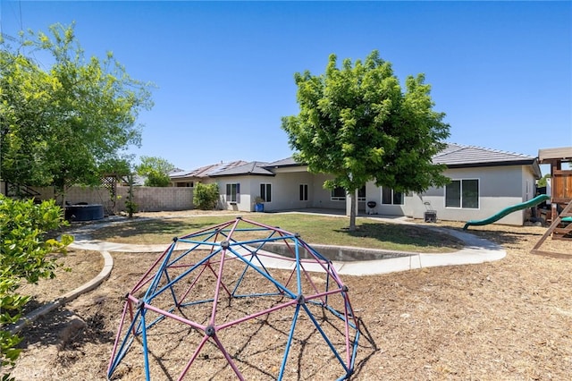 back of house featuring a playground and stucco siding