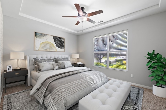 bedroom with a raised ceiling, carpet floors, baseboards, and ceiling fan
