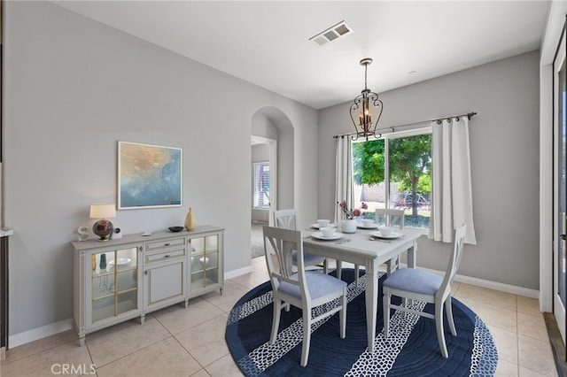 dining room featuring arched walkways, light tile patterned flooring, baseboards, and a chandelier