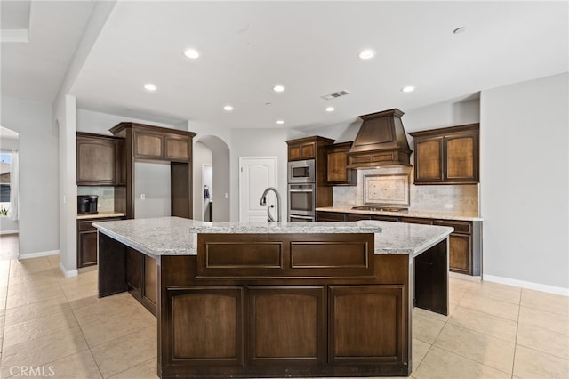 kitchen with arched walkways, stainless steel appliances, light tile patterned floors, tasteful backsplash, and recessed lighting