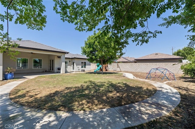fenced backyard with ceiling fan, a playground, and a patio