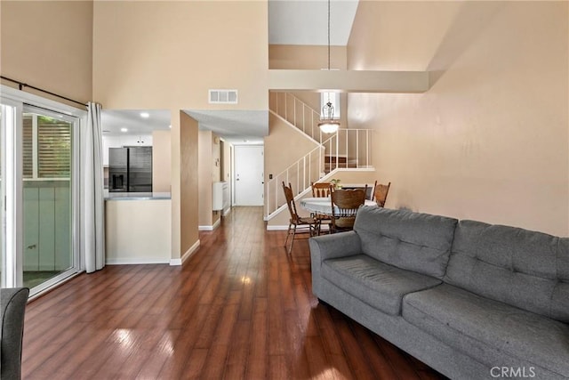 living area featuring wood finished floors, stairway, a high ceiling, and baseboards