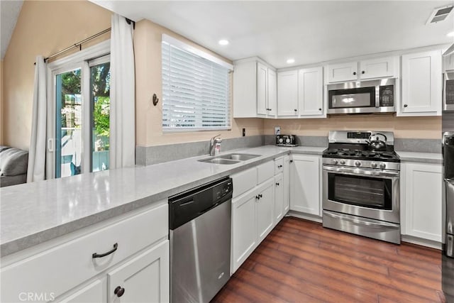 kitchen with appliances with stainless steel finishes, a sink, white cabinets, recessed lighting, and dark wood finished floors