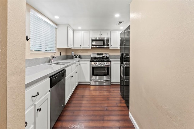 kitchen featuring appliances with stainless steel finishes, a sink, light countertops, white cabinets, and dark wood-style floors