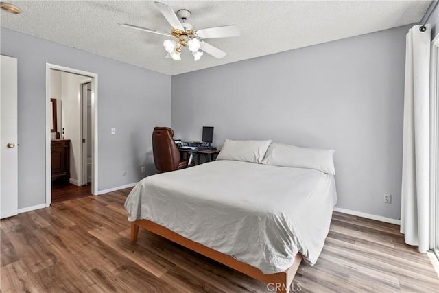 bedroom with wood finished floors, baseboards, a textured ceiling, and connected bathroom