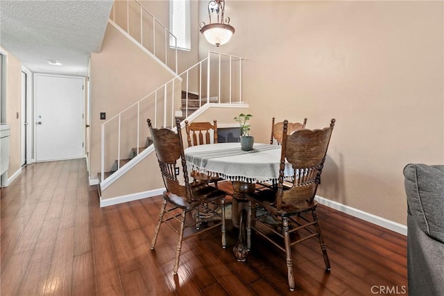 dining room featuring stairs, wood finished floors, baseboards, and a textured ceiling