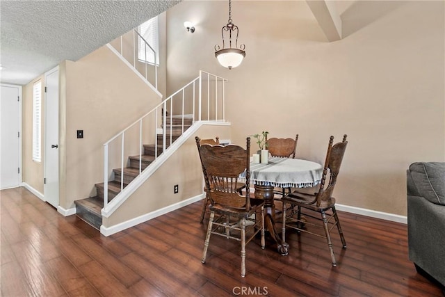dining room featuring stairs, wood finished floors, baseboards, and a textured ceiling