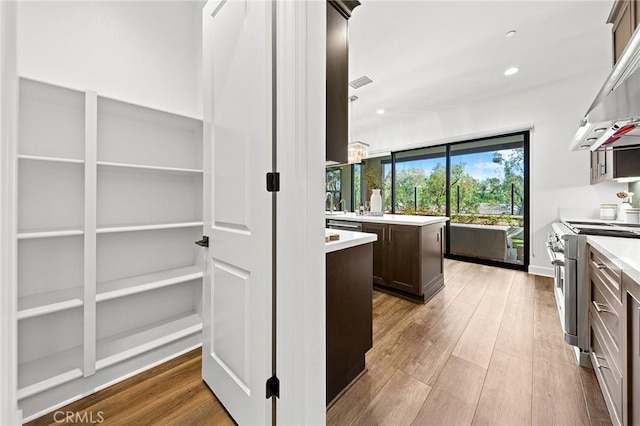 27 Alessio, Lake Forest, CA 92630 - kitchen with appliances with stainless steel finishes, range hood, dark brown cabinets, light countertops, and wood finished floors
