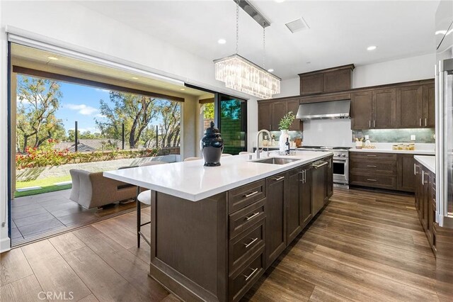 27 Alessio, Lake Forest, CA 92630 - kitchen with wall chimney exhaust hood, high end stainless steel range oven, light countertops, dark wood finished floors, and dark brown cabinets