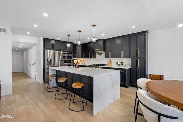 3960 W Hemlock St, Oxnard, CA 93035 - kitchen featuring appliances with stainless steel finishes, light stone counters, recessed lighting, decorative backsplash, and a kitchen island with sink