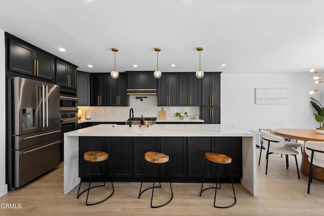 3960 W Hemlock St, Oxnard, CA 93035 - kitchen with appliances with stainless steel finishes, decorative backsplash, light stone countertops, a breakfast bar area, and light wood-style flooring