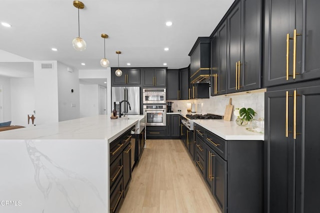3960 W Hemlock St, Oxnard, CA 93035 - kitchen with appliances with stainless steel finishes, decorative backsplash, light wood-style flooring, light stone counters, and recessed lighting