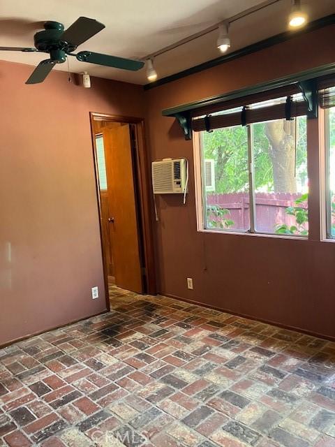 9656 Green Verdugo Dr, Shadow Hills, CA 91040 - spare room with an AC wall unit, ceiling fan, brick floors, and rail lighting